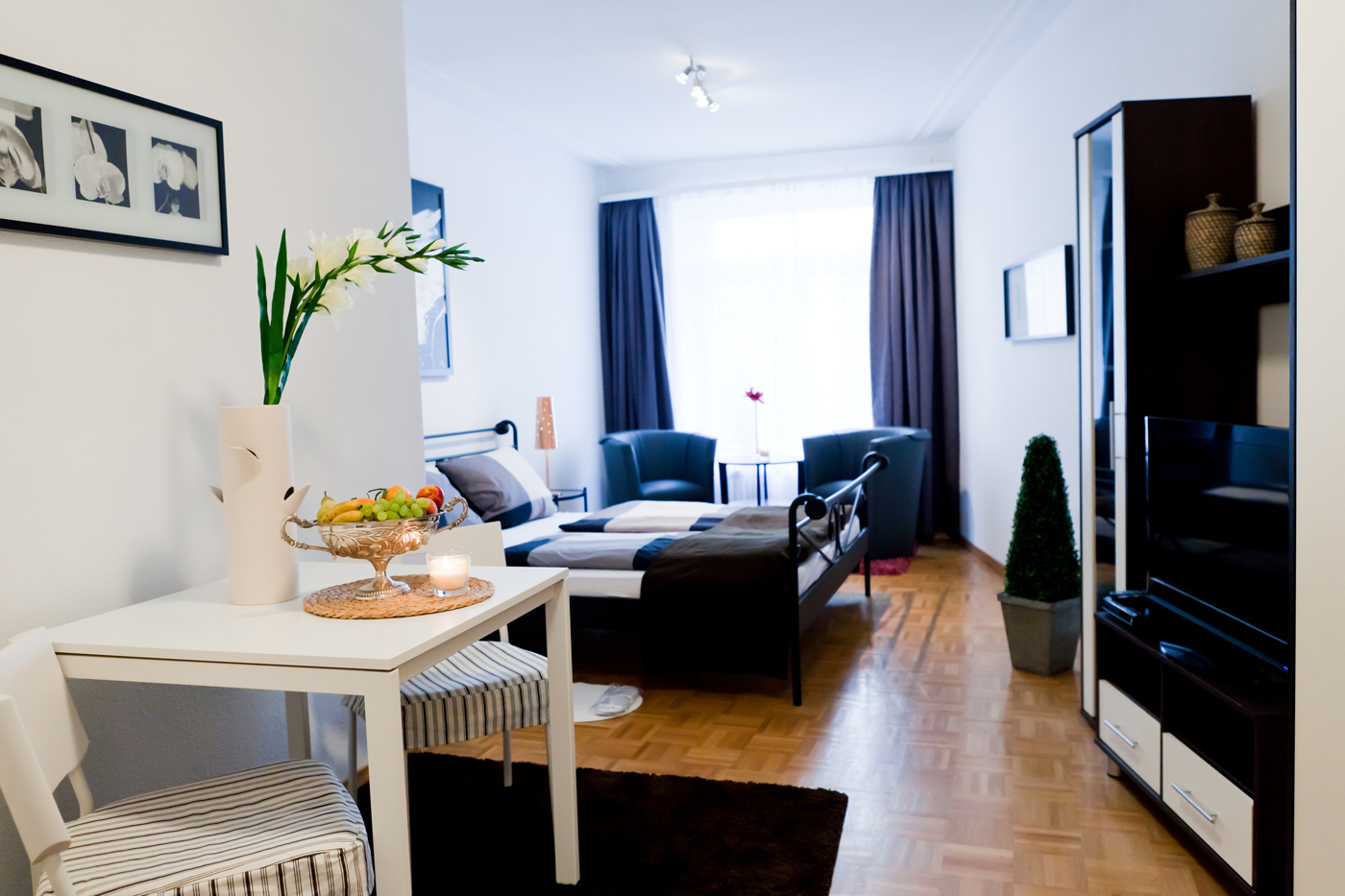 Doppelbett, Sitzmöglichkeit und TV im Appartement in Baden-Baden.